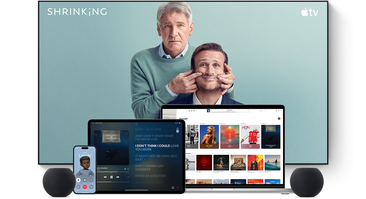 Large flat screen television showing two male characters from the Apple TV+ series shrinking. A MacBook Pro, an iPad, an iPhone, and a Midnight HomePod mini are arranged in front.