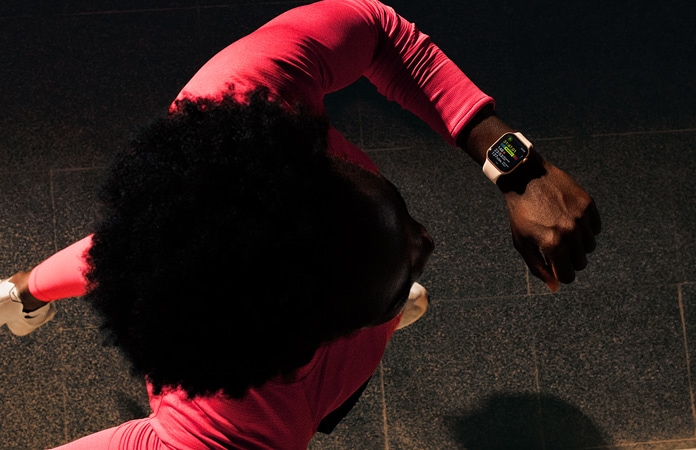 Valaki futás közben megnézi az edzésadatait az Apple Watch Series 11 Edzés alkalmazásában