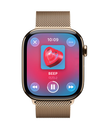 밀레니즈 루프 밴드가 장착된 골드 티타늄 Apple Watch, Apple Music을 재생 중인 시계 페이스, 반투명 Liquid Glass 제어 항목