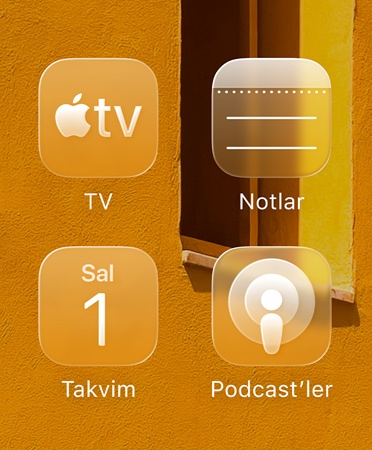 Apple TV uygulaması, Notlar, Takvim ve Podcast’ler olmak üzere dört yarı saydam uygulama simgesinden oluşan ızgara arka planı yansıtıyor
