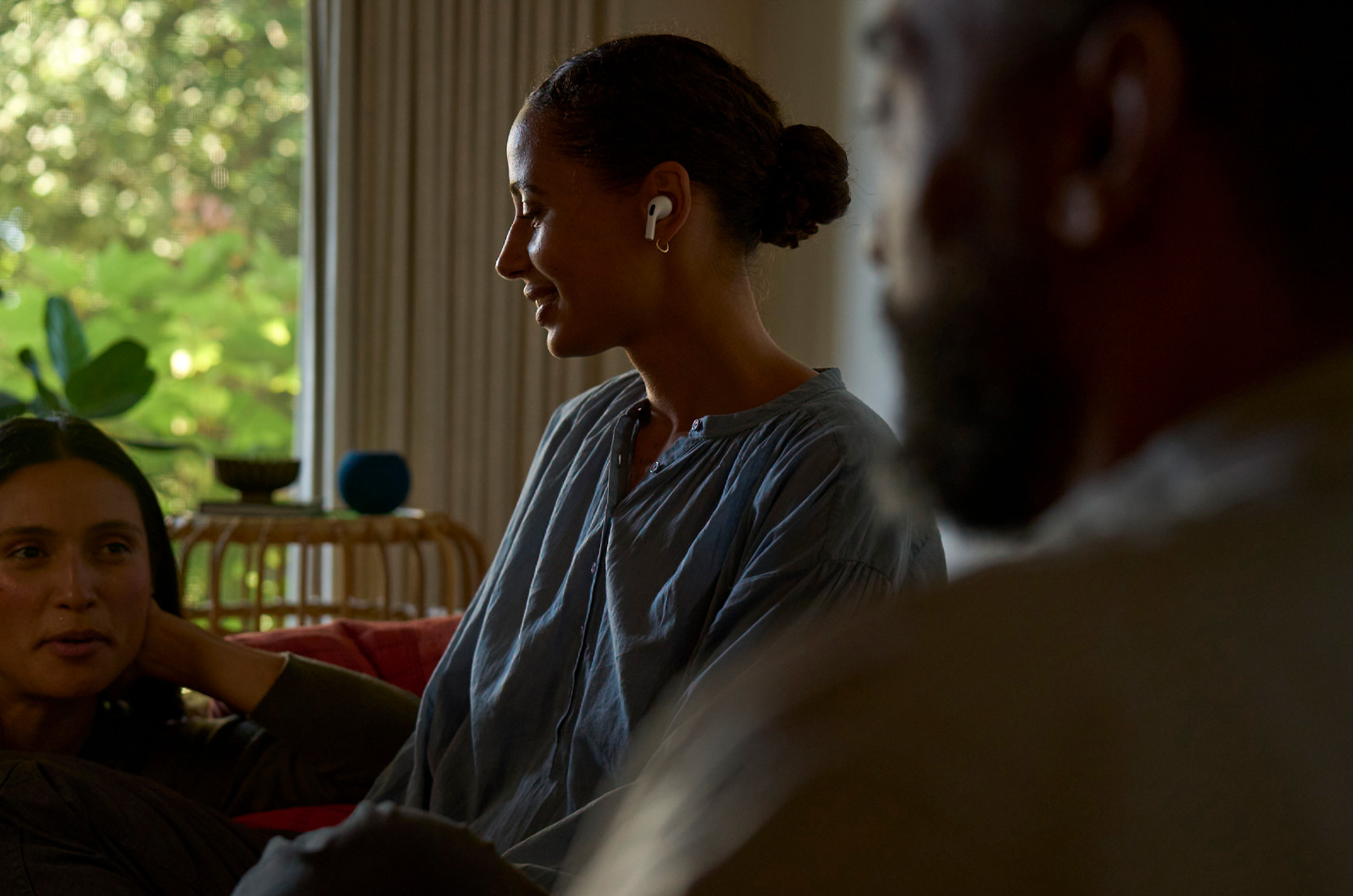 Foto tampak samping seorang wanita yang mengenakan AirPods Pro 2 di telinga kiri dan menggunakan fitur Kesehatan Pendengaran