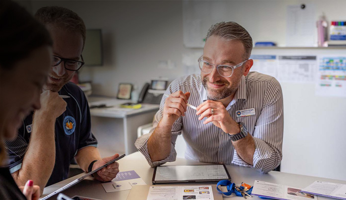 A faculty member holds Apple Pencil while sitting at a table