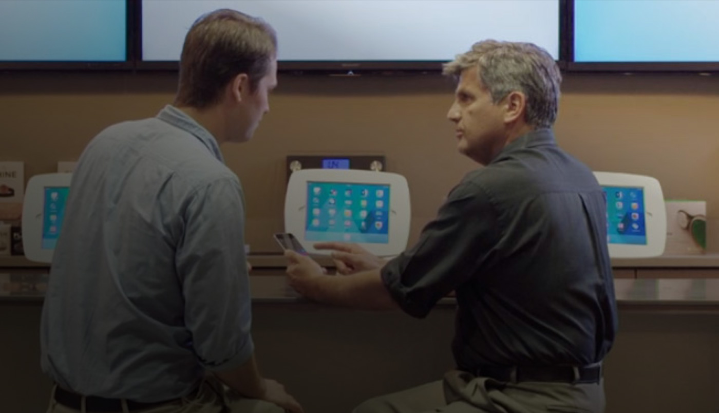 Two men sitting at the O Bar, looking at an iPhone screen.