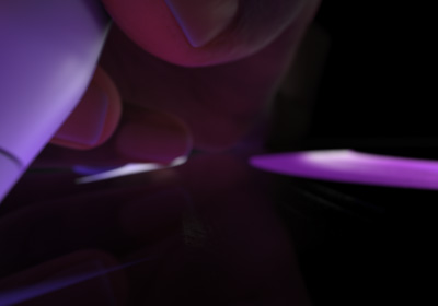 Une main tenant un Apple Pencil Pro s’apprête à écrire. La pointe appuie sur un écran, qui affiche des lignes épaisses tracées en violet vif.