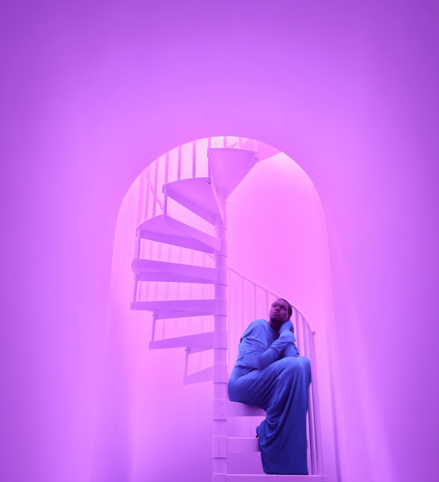 Close-up of a woman sitting on a spiral staircase demonstrating the pro camera system’s low-light photographic capabilities.