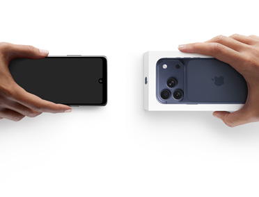 Hands exchanging phones, Android on the left without a box, on the right is a new iPhone 17 Pro in box