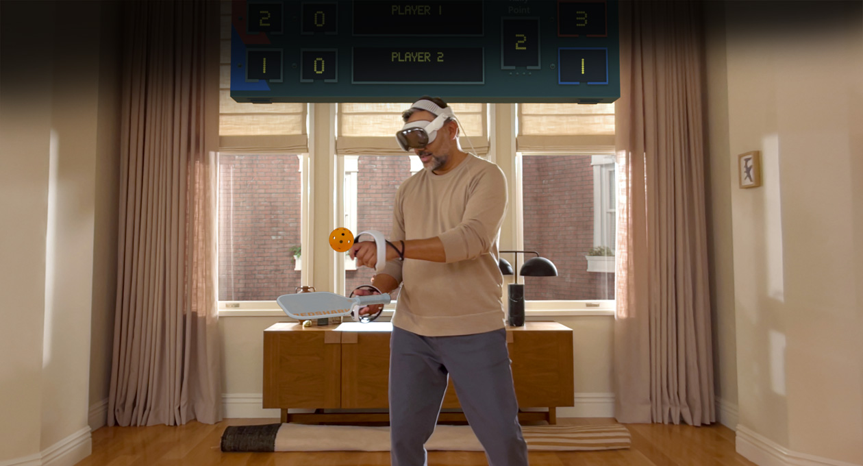 Apple Vision Pro와 Sony PlayStation VR2 Sense 컨트롤러를 착용하고 Pickle Pro 게임을 하는 남자의 모습, 그리고 그 위에 떠 있는 공간 점수판