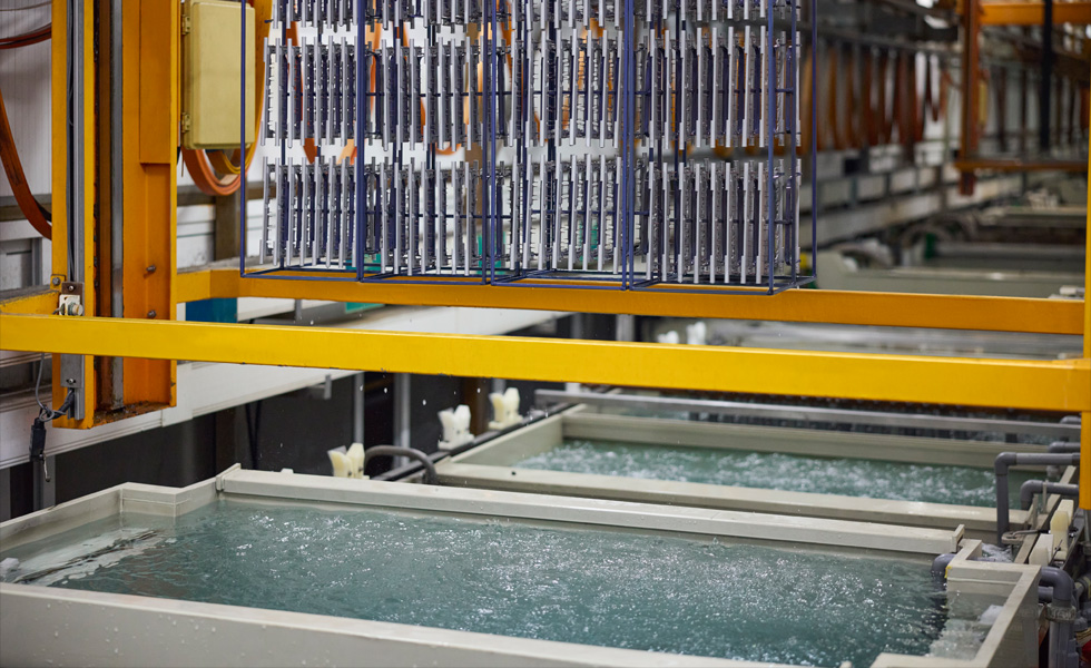 A machine on the component manufacturing line with water dripping off of it into a vat of water underneath it